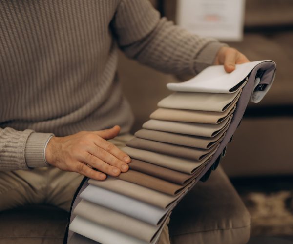 A,Man,Is,Holding,A,Catalogue,Of,Sofa,Colours,And